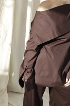 Woman wearing a pure cotton brown shirt by Kureé The Brand Womenswear standing against a draped backdrop