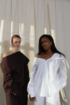 Woman wearing a pure cotton espresso brown and crisp white shirt worn both ways by Kureé The Brand Womenswear standing against a draped backdrop